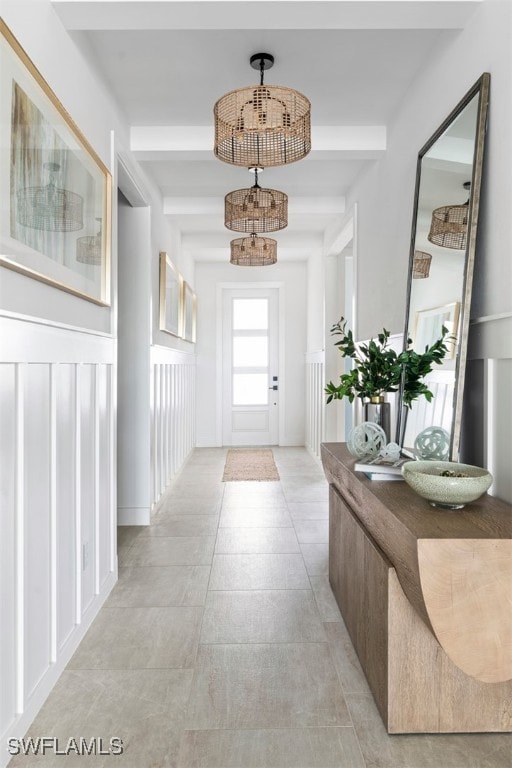 hallway featuring beamed ceiling, light tile patterned flooring, and a notable chandelier