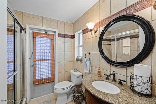 bathroom featuring toilet, an enclosed shower, tile walls, and vanity