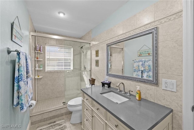 bathroom featuring tile patterned floors, vanity, tiled shower, tile walls, and toilet