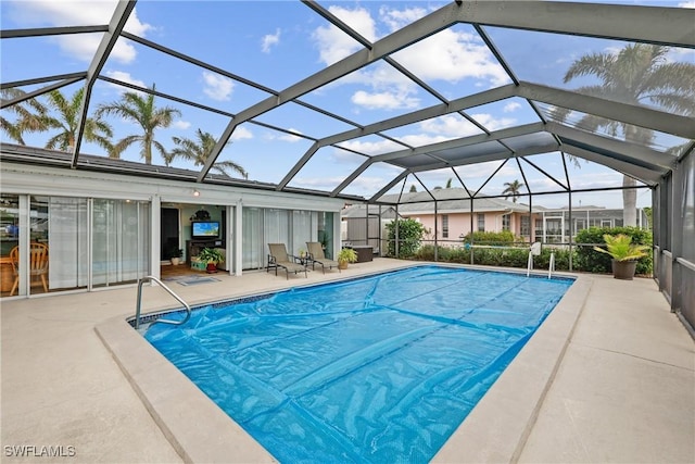 view of pool with glass enclosure and a patio area