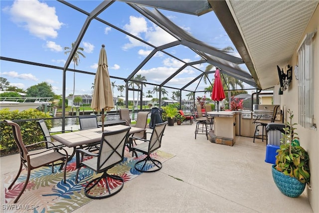 view of patio with glass enclosure, an outdoor kitchen, a grill, an outdoor bar, and a water view