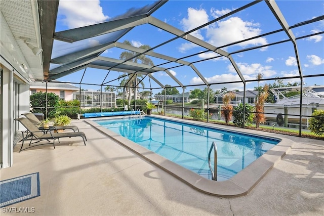 view of pool featuring glass enclosure, a water view, and a patio