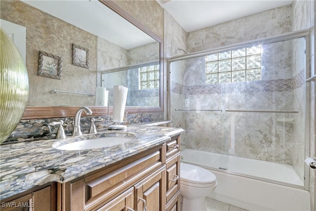 full bathroom featuring vanity, a healthy amount of sunlight, toilet, and enclosed tub / shower combo