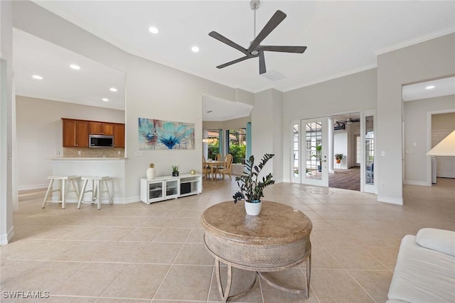 tiled living room with ceiling fan, crown molding, and french doors