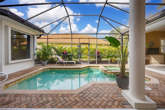 view of pool with a lanai, a patio area, and an in ground hot tub