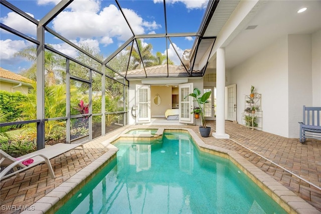 view of pool with glass enclosure, a patio area, and an in ground hot tub