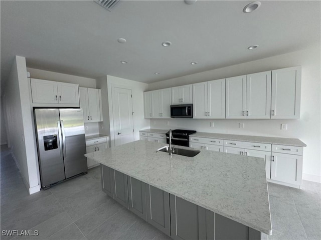 kitchen featuring sink, white cabinetry, light stone counters, a center island with sink, and stainless steel appliances