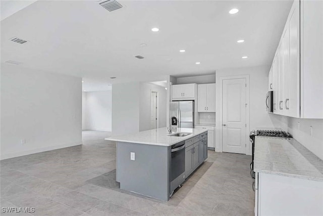 kitchen with sink, gray cabinetry, white cabinetry, appliances with stainless steel finishes, and an island with sink