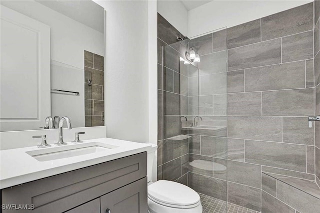 bathroom featuring tiled shower, vanity, and toilet