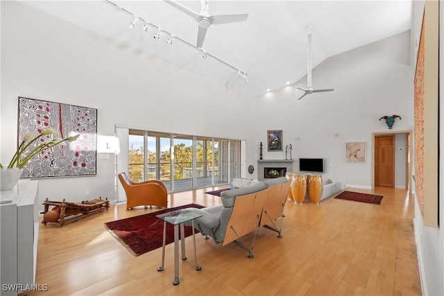 living room with rail lighting, high vaulted ceiling, ceiling fan, and light hardwood / wood-style flooring