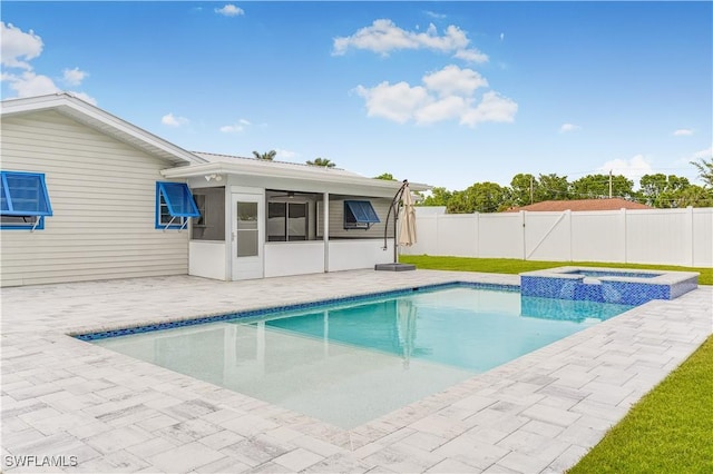 view of pool with an in ground hot tub, a patio area, and a sunroom