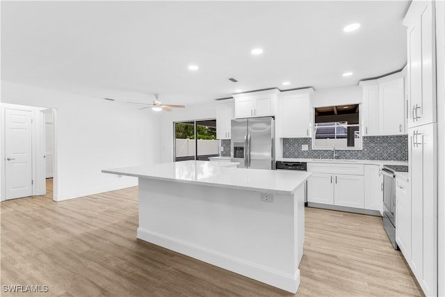 kitchen with decorative backsplash, appliances with stainless steel finishes, sink, white cabinets, and a kitchen island