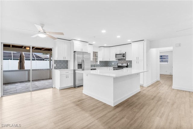 kitchen with light hardwood / wood-style flooring, white cabinets, stainless steel appliances, and a kitchen island