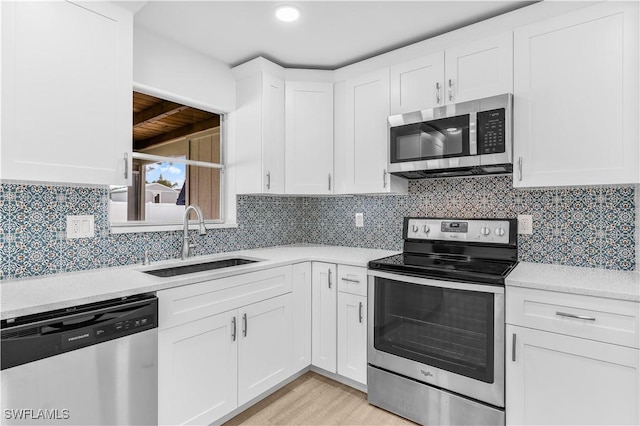 kitchen with stainless steel appliances, white cabinetry, tasteful backsplash, and sink