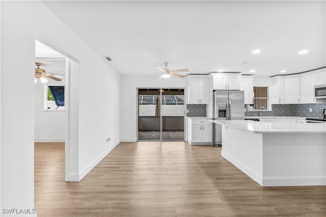 kitchen featuring backsplash, white cabinets, sink, light wood-type flooring, and stainless steel appliances