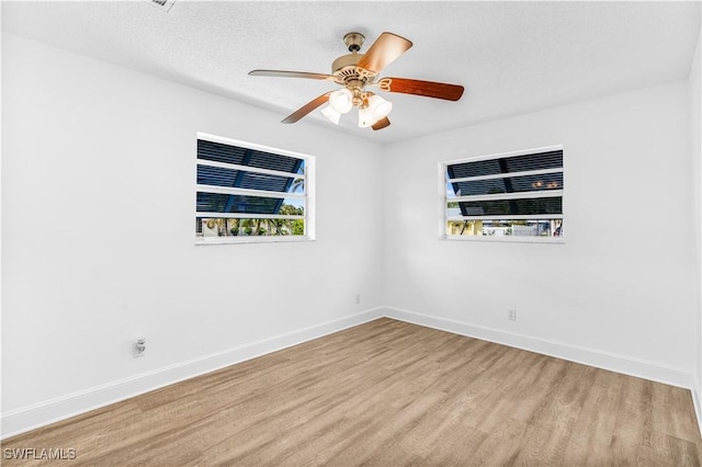 empty room with ceiling fan, a textured ceiling, and light wood-type flooring