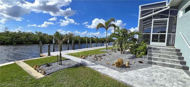 view of yard featuring glass enclosure, a water view, and a boat dock