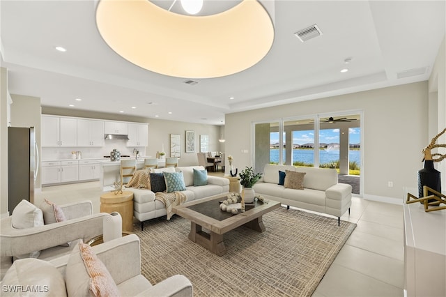 living area featuring light tile patterned floors, recessed lighting, a tray ceiling, and visible vents