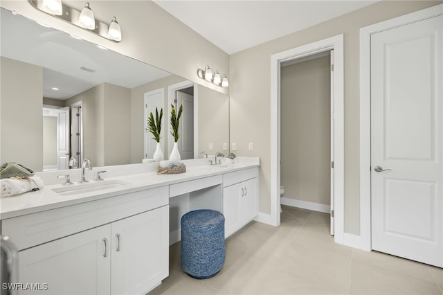 full bath featuring double vanity, a sink, toilet, and tile patterned floors