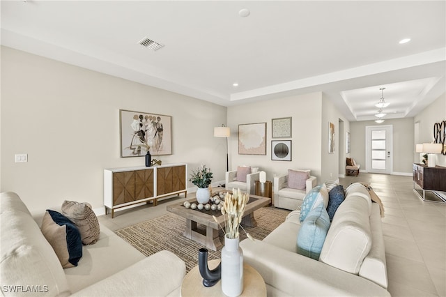 living room featuring a raised ceiling, recessed lighting, light tile patterned floors, and visible vents