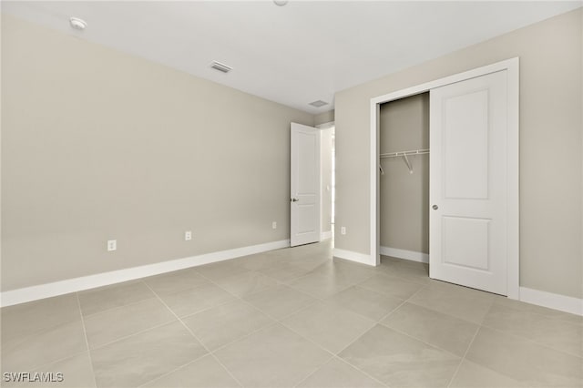 unfurnished bedroom featuring baseboards, visible vents, a closet, and light tile patterned flooring