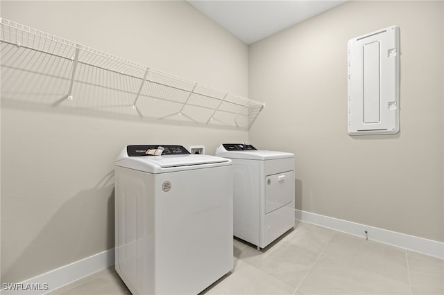 laundry area with electric panel, baseboards, laundry area, washer and clothes dryer, and light tile patterned floors