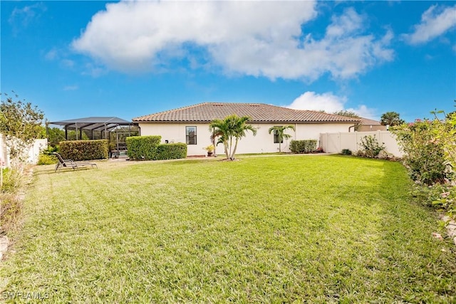 back of house featuring a lawn and a lanai