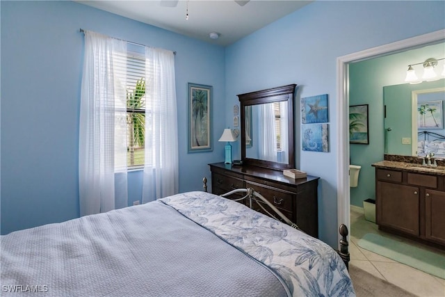 bedroom featuring ceiling fan, ensuite bathroom, light tile patterned floors, and sink