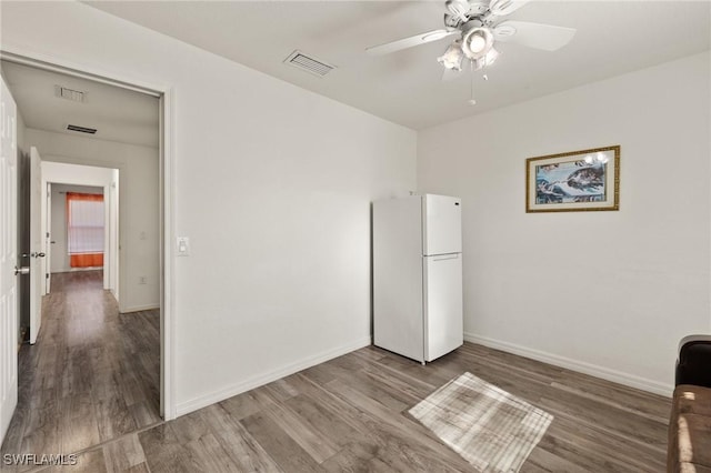 unfurnished bedroom with hardwood / wood-style floors, ceiling fan, white fridge, and a closet