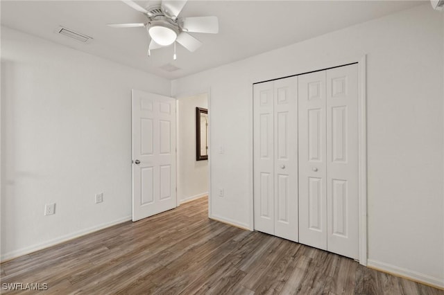 unfurnished bedroom with ceiling fan, wood-type flooring, and a closet