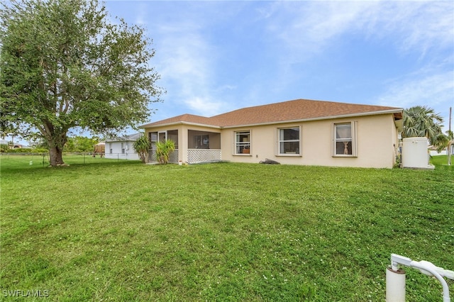 back of property with a lawn and a sunroom