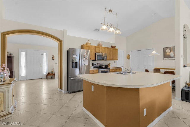 kitchen with appliances with stainless steel finishes, sink, light tile patterned floors, pendant lighting, and a center island with sink