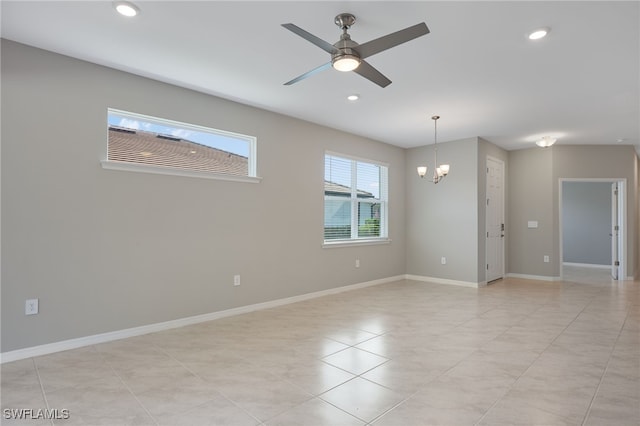 tiled spare room with ceiling fan with notable chandelier