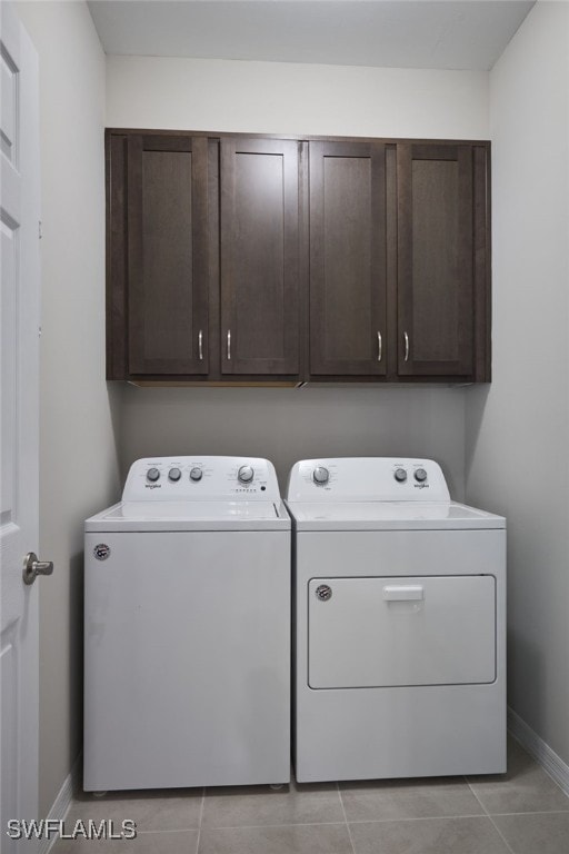 laundry area with washer and dryer, light tile patterned floors, and cabinets