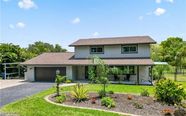 front facade with covered porch, a front yard, and a garage