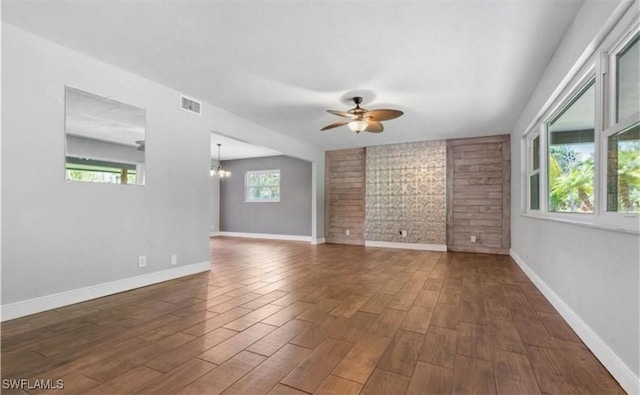 spare room featuring ceiling fan with notable chandelier