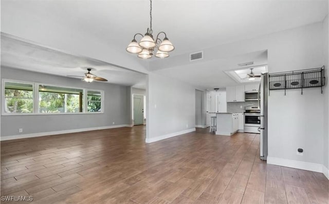 unfurnished living room featuring ceiling fan with notable chandelier and hardwood / wood-style flooring