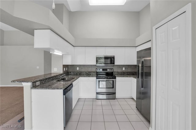 kitchen with sink, light tile patterned flooring, kitchen peninsula, white cabinets, and appliances with stainless steel finishes