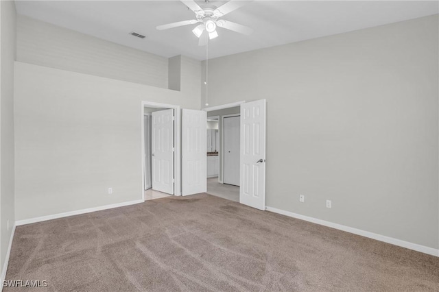 unfurnished bedroom with light carpet, a towering ceiling, and ceiling fan