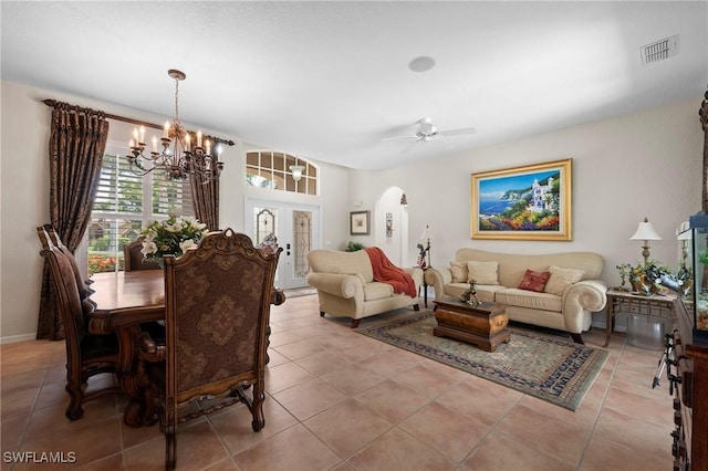 tiled dining space with ceiling fan with notable chandelier and french doors