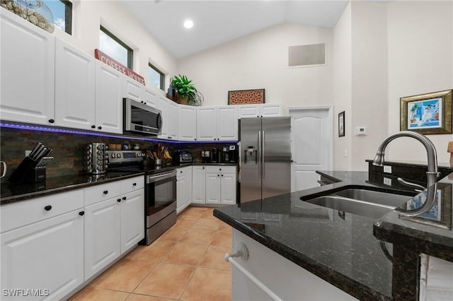 kitchen with sink, decorative backsplash, dark stone countertops, appliances with stainless steel finishes, and white cabinetry