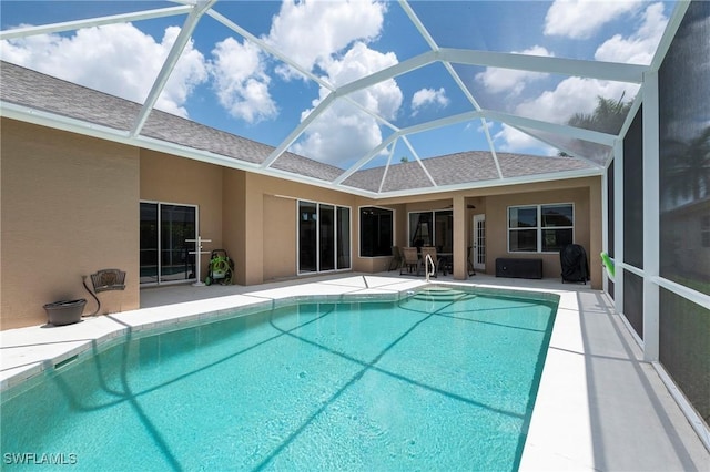 view of swimming pool featuring glass enclosure and a patio area