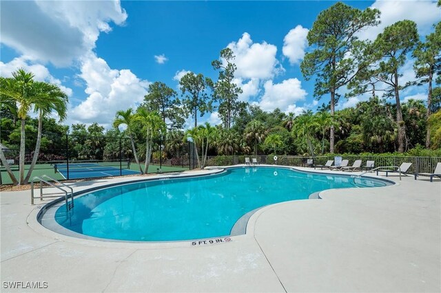 view of swimming pool featuring tennis court