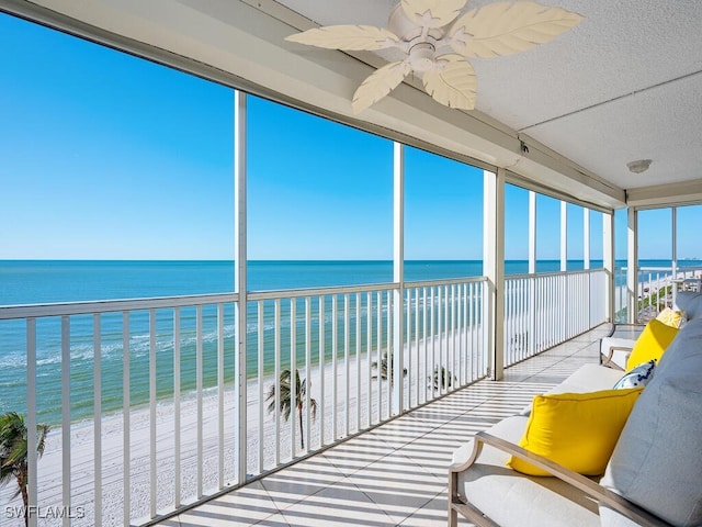 unfurnished sunroom featuring a water view and a view of the beach