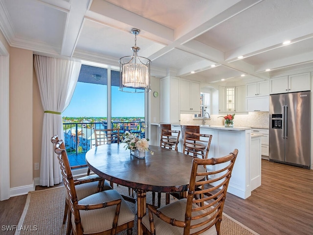 dining space featuring beam ceiling, hardwood / wood-style flooring, an inviting chandelier, and ornamental molding