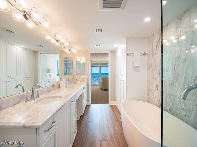 bathroom featuring vanity, a water view, wood-type flooring, and a tub