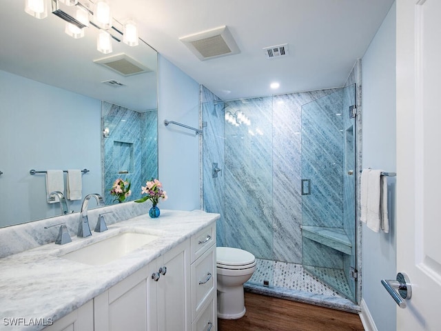 bathroom with hardwood / wood-style floors, vanity, toilet, and a shower with shower door