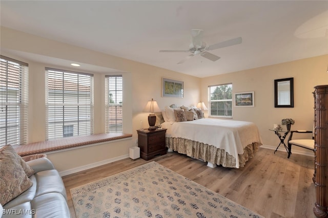 bedroom featuring ceiling fan, light hardwood / wood-style floors, and multiple windows