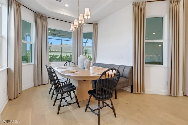 dining room with a raised ceiling, crown molding, light hardwood / wood-style flooring, and ceiling fan