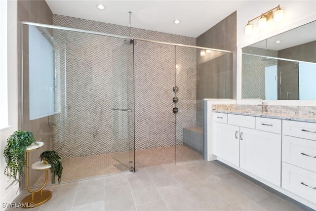 bathroom with tile patterned flooring, vanity, and tiled shower